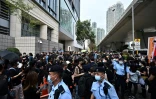 Des agents de police passent entre les manifestants postés devant le tribunal de Kowloon à Hong-Kong le 1er mars 2021 
