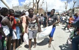 Des victimes de l'ouragan Matthew transportent un sac de nourriture distribué par le Programme alimentaire mondial, le 12 octobre 2016 en Haïti