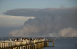 Des touristes regardent le 14 juillet 2022 depuis la jetée d'Andernos-les-Bains, en Gironde, la fumée du violent incendie qui ravage la forêt de la Teste-de-Buch