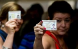 Deux Vénézueliennes montrent leur carte d'identité, à Caracas, le 20 juin 2016