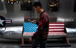 Un homme passe devant un banc décoré d'un drapeau américain devant un magasin à Pékin le 15 mai 2019