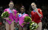 L'Américaine Simone Biles, au centre, médaille d'or autour du cou, sur le podium du concours général des championnats du monde de gymnastique le 4 octobre 2013 à Anvers, avec sa compatriote Kyla Ross (à gauche) et la Russe Aliya Mustafina
