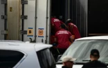 Des employés de la morgue déposent un sac mortuaire dans un conteneur de stockage réfrigéré, le 15 août 2023 sur l'île de Maui, à Hawaï