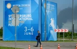 Un homme passe devant des affiches du Forum économique international de Saint-Pétersbourg alors que de  la fumée s'élève en arrière-plan après des frappes de drones ukrainiens, le 3 juin 2026