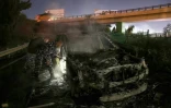 Des policiers inspectent l'épave d'un véhicule calciné de la Finul, incendié par des manifestants, sur la route menant à l'aéroport de Beyrouth, le 14 février 2025 au Liban
