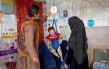 Hasina et son époux Nureddin (g), volontaires dans le cadre d'un programme de l'Unicef, pèsent des enfants our évaluer leur niveau de malnutrition dans un poste de santé du village de Gandanchusma, dans la province de Badakhshan, le 25 février 2024 en Afghanistan
