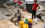 Des enfants gazaouis remplissent des bidons d'eau à une canalisation, à Beit Lahia, dans le nord de la bande de Gaza, le 24 avril 2025
