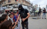 Un membre des forces de sécurité intérieure loyales au groupe palestinien Hamas salue de s enfants dans le camp de réfugiés de Nousseirat, dans le centre de la bande de Gaza, le 12 octobre 2025