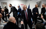 Le ministre de l'Intérieur Gerard Collomb (au centre) serre la main à un réfugié qui a signé un contrat d'intégration républicaine le 19 février 2018 à Lyon
