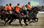 Les cavaliers de l'équipe Yama Petroleum (en orange) en compétition avec l'équipe Baghlan lors de la finale du tournoi de bouzkachi, le 8 mars 2024 à Mazar-i-Sharif, en Afghanistan