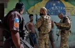 Des policiers vérifient l'identité de deux hommes pendant une opération contre le trafic de drogue dans la favela de Jacarezinho, le 19 janvier 2022 à Rio de Janeiro, au Brésil