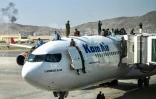 Des Afghans grimpés sur la carlingue d'un avion de la compagne afghane Kam Air à l'aéroport de Kaboul, le 16 août 2021, alors que des milliers de personnes essaient de fuir le pays après la prise de Kaboul par les talibans