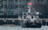 Les patins d'atterrissage d'un hélicoptère (g) à la surface de l'eau à côté d'un bateau de l'US Army Corps of Engineers au large de Hoboken, dans le New Jersey, après son crash dans le fleuve Hudson, le 10 avril 2025