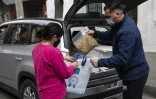Un employé de la municipalité de Santiago apporte un repas préparé par le restaurant "Ambrosia", à une mère de famille dans le besoin, le 14 août 2020