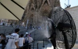 Un ventilateur brumisateur rafraĂ®chit les touristes qui visitent la Sagrada FamĂlia Ă Barcelone, le 7 juillet 2026, lors d'une vague de chaleur en Espagne