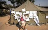 Une femme passe devant les listes électorales d'un bureau de vote lors des élections présidentielles et législatives, le 24 août 2023 à Harare, au Zimbabwe