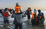 Des migrants avancent dans l'eau pour embarquer sur le bateau d'un passeur et tenter de traverser la Manche au large de la plage de Gravelines, le 16 juin 2025 dans le Nord