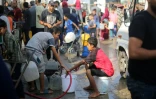 Des Palestiniens remplissent des seaux d'eau à un point de distribution dans le camp de réfugiés de Nousseirat, dans le centre de la bande de Gaza, le 10 juillet 2025