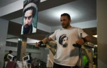 Un bodybuilder porte un T-shirt flanqué d'un portrait du commandant Massoud, le 4 mai 2019 à Kaboul dans une salle de sport où est aussi suspendu un portrait de Massoud