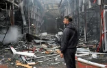 Un homme observe les dégâts alors qu'un pompier ukrainien éteint un incendie au marché "Barabashovo" après une attaque de drone à Kharkiv, le 6 mai 2025 en Ukraine