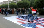 Des partisans d'une faction pro-iranienne, Assaïb Ahl al-Haq, défilent dans le centre de Bagdad en piétinant le drapeau américain, le 14 décembre 2019 en Irak