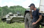 Un fermier remorque un blindé de transport de troupes russe abandonné près du village de Mala Rogan, dans la région de Kharkiv, le 28 juillet 2022