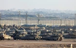Une photo prise depuis la frontière israélienne avec la bande de Gaza montre des véhicules blindés militaires israéliens stationnés face aux bâtiments détruits dans le territoire palestinien, le 16 septembre 2025