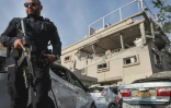 Un policier israélien debout devant un bâtiment endommagé par un tir de roquette depuis le sud du Liban, dans la ville de Tira dans le centre d'Israël, le 2 novembre 2024