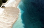 Vue aérienne d'un engin de chantier draguant du sable pour agrandir une plage artificielle à Primosten, le 9 mai 2025 en Croatie