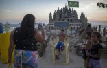 Des gens prennent des photos du château de sable de Marcio Mizael Matolias, le 18 janvier 2018 sur la plage de Barra da Tijuca, à Rio de Janeiro