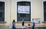 Une enfant pointe du doigt une bannière dénonçant les températures extrêmes en classe dans une école de Paris le 18 juin 2026