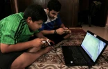 Des garçons palestiniens jouent sur l'ordinateur profitant de quelques heures d'électricité dans le camp de réfugiés à Rafah, dans la bande de Gaza, le 23 juillet 2017