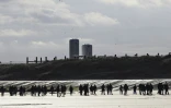 Des migrants sur la plage de Gravelines se dirigent vers un bateau de passeurs pour traverser la Manche, le 26 avril 2024 près de Dunkerque, dans le nord de la France