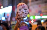 Un manifestant tient un masque sur lequel sont inscrits des slogans, le 5 octobre 2019 à Hong Kong