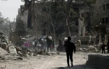 Des civils fuient leurs maisons détruites dans la ville de Hammouriyé dans le secteur rebelle de la Ghouta orientale, cible d'une offensive du régime syrien, le 15 mars 2018