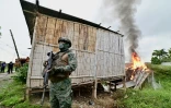 Un soldat monte la garde devant une maison en flammes utilisée comme cache par des criminels, lors d'une opération conjointe des forces armées et de la police nationale à Duran, en Equateur, le 15 janvier 2025