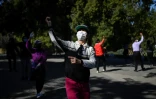 Des femmes portant des masques de protection dansent dans un parc de Pékin, le 13 mars 2020