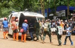 Des équipes de secours lors d'un exercice d'évacuation sur une route boueuse menant à la grotte de Tham Luang où sont piégés douze enfants et leur entraîneur de foot, le 30 juin 2018 à Chiang Rai, en Thaïlande