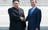 Moon Jae-in (d) et Kim Jong Un se serrent la main sur la ligne de démarcation avant le début du sommet, le 27 avril 2018 à Panmunjom