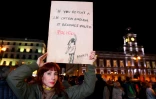 Une femme brandit une affiche représentant une oeuvre de Banksy lors d'une manifestation contre le parti espagnol d'extrême droite Vox, le 15 janvier 2019 à Madrid