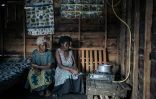 Deux femmes bénéficiaires d'un projet pilote du WWF visant à produire du biogaz domestique, regardent leur nouveau réchaud à gaz, à Sake, le 28 septembre 2019 en RDC