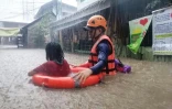Un agent des garde-côtes aide une habitante de Cagayan de Oro, dans l'île philippine de Mindanao, à évacuer son domicile pendant des inondations apportées par le super-typhon Rai, le 16 décembre 2021