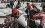 Women carry sacks of wheat during a distribution of food organised by the Ethiopian government in the city of Alamata in December 2020 