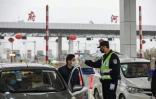 Un policier contrôle la température d'un automobiliste à un péage autoroutier, le 24 janvier 2020 à Wuhan, épicentre du nouveau coronavirus en Chine