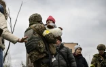 Un militaire ukrainien porte un enfant tout en aidant les gens à traverser un pont détruit alors qu'ils évacuent la ville d'Irpin, au nord-ouest de Kiev, le 5 mars 2022