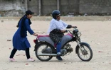 L'instructrice Shafaq Zaman (g) apprend Ă conduire une moto Ă une femme du groupe "Rowdy Riders", le 5 mars 2024 Ă Karachi, au Pakistan
