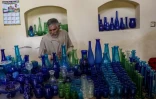 Le souffleur de verre Ghulam Sakhi Saifi montre des objets en verre dans la boutique de son atelier, le 11 août 2024 à Hérat, en Afghanistan