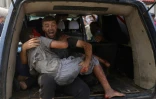 Un homme évacue un jeune blessé après une frappe israélienne à Gaza-ville, le 12 août 2025