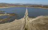 Vue aérienne montrant un tronçon de l'ancienne autoroute reliant Izmir à Cesme, en Turquie, émergeant en raison de la baisse de niveau de la retenue d'eau d'un barrage à Izmir, le 30 juillet 2025