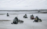 Des touristes en motoneiges électriques, le 8 mai 2022 à Longyearbyen, dans l'archipel du Svalbard, en Arctique